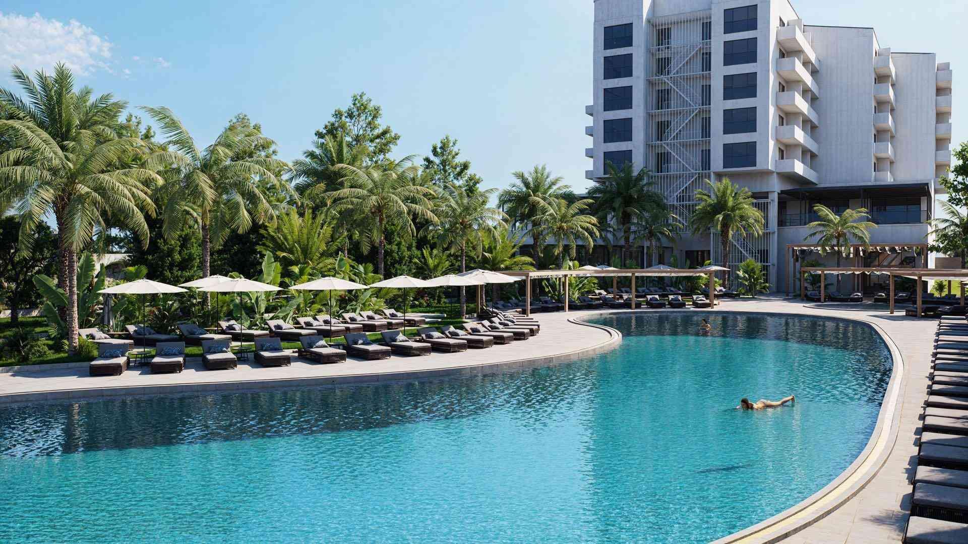 Großer Hotelpool mit Liegen, Palmen und hohem Gebäude bei klarem Himmel.