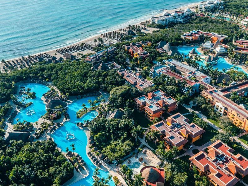 Großes Hotelresort mit weitläufigen Lagunenpools, grüner Vegetation und direktem Zugang zum Sandstrand am Meer.
