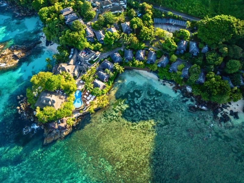 Tropisches Resort an der Küste mit Bungalows, üppiger Vegetation und klarem, türkisfarbenem Wasser.