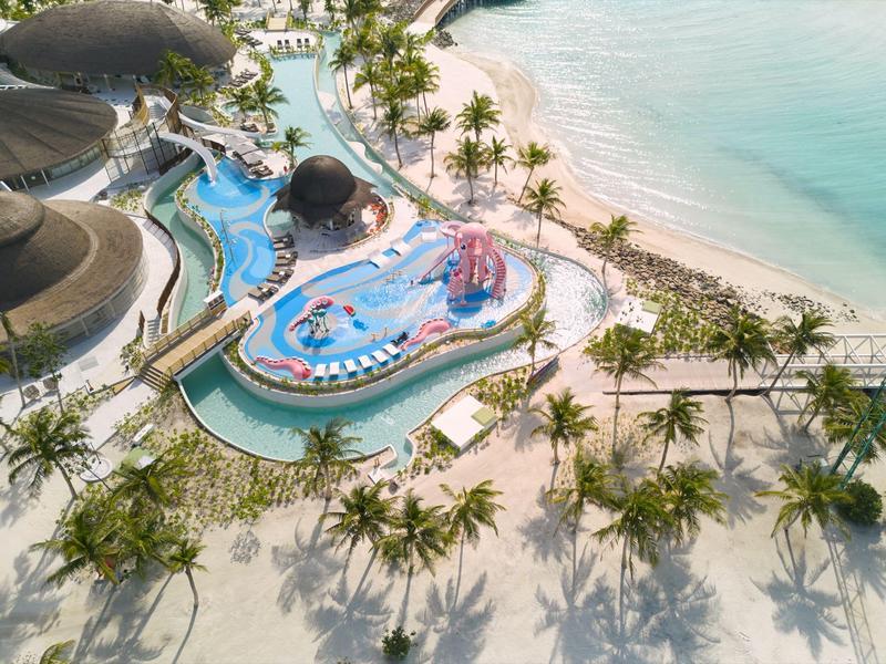 Tropisches Strandhotel mit Pools, Wasserrutschen und Palmen direkt am türkisfarbenen Meer.