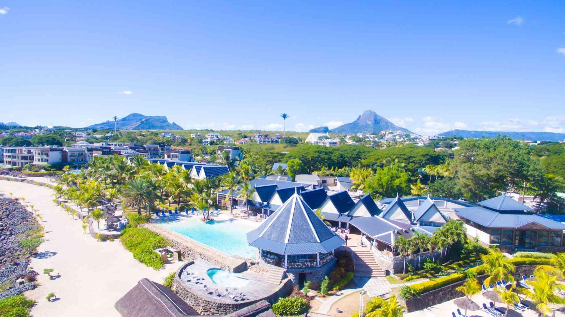 Luxuriöses Hotel mit Pool, Palmen und Bergen im Hintergrund, ideal für einen entspannten Urlaub.