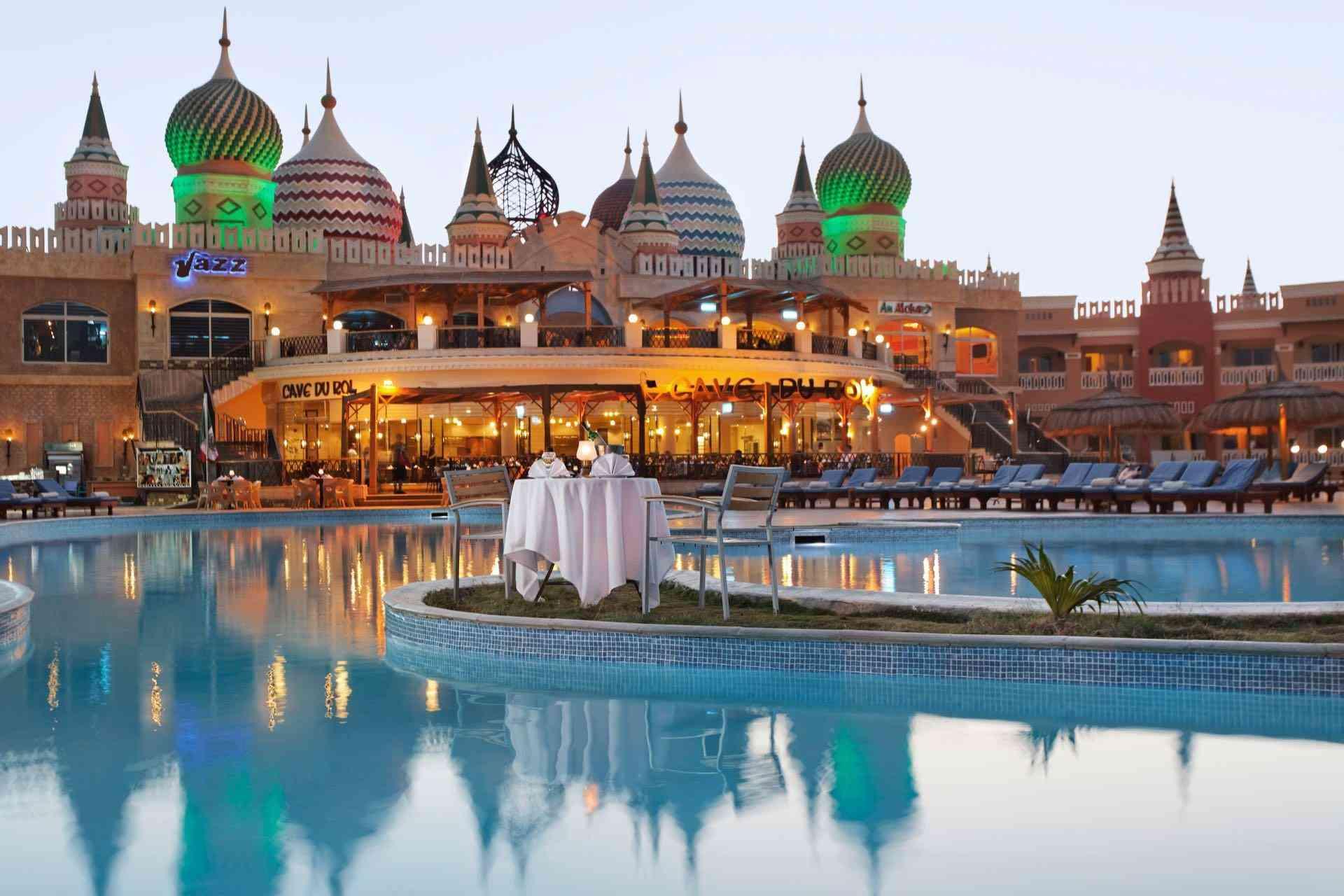 Luxuriöse Hotelanlage mit bunten Kuppeln und großem Pool, gedeckter Tisch für zwei Personen.
