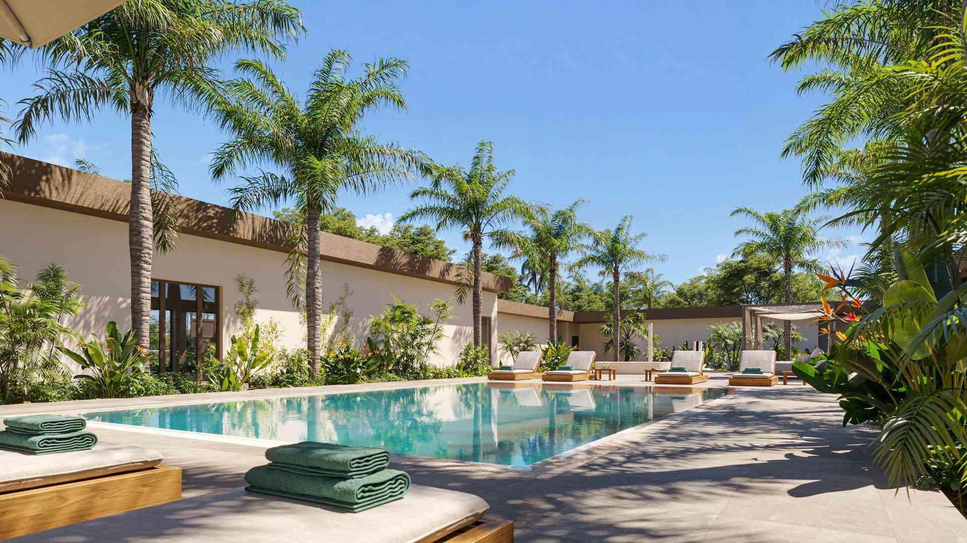 Hotelpool mit Liegen, Palmen und klarem blauem Himmel in entspannter Urlaubsatmosphäre.