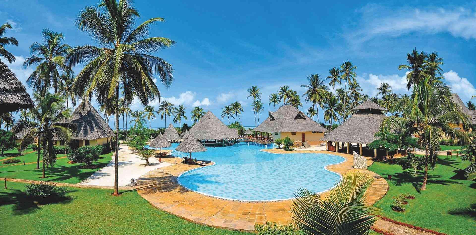 Hotelanlage mit Pool, Palmen und tropischen Bungalows unter klarem blauem Himmel.