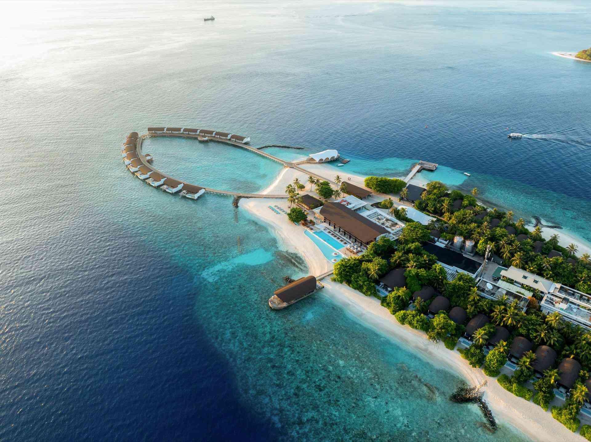 Luxuriöses Hotel auf tropischer Insel mit Wasserbungalows, weißem Sandstrand und klarem, blauem Meer.