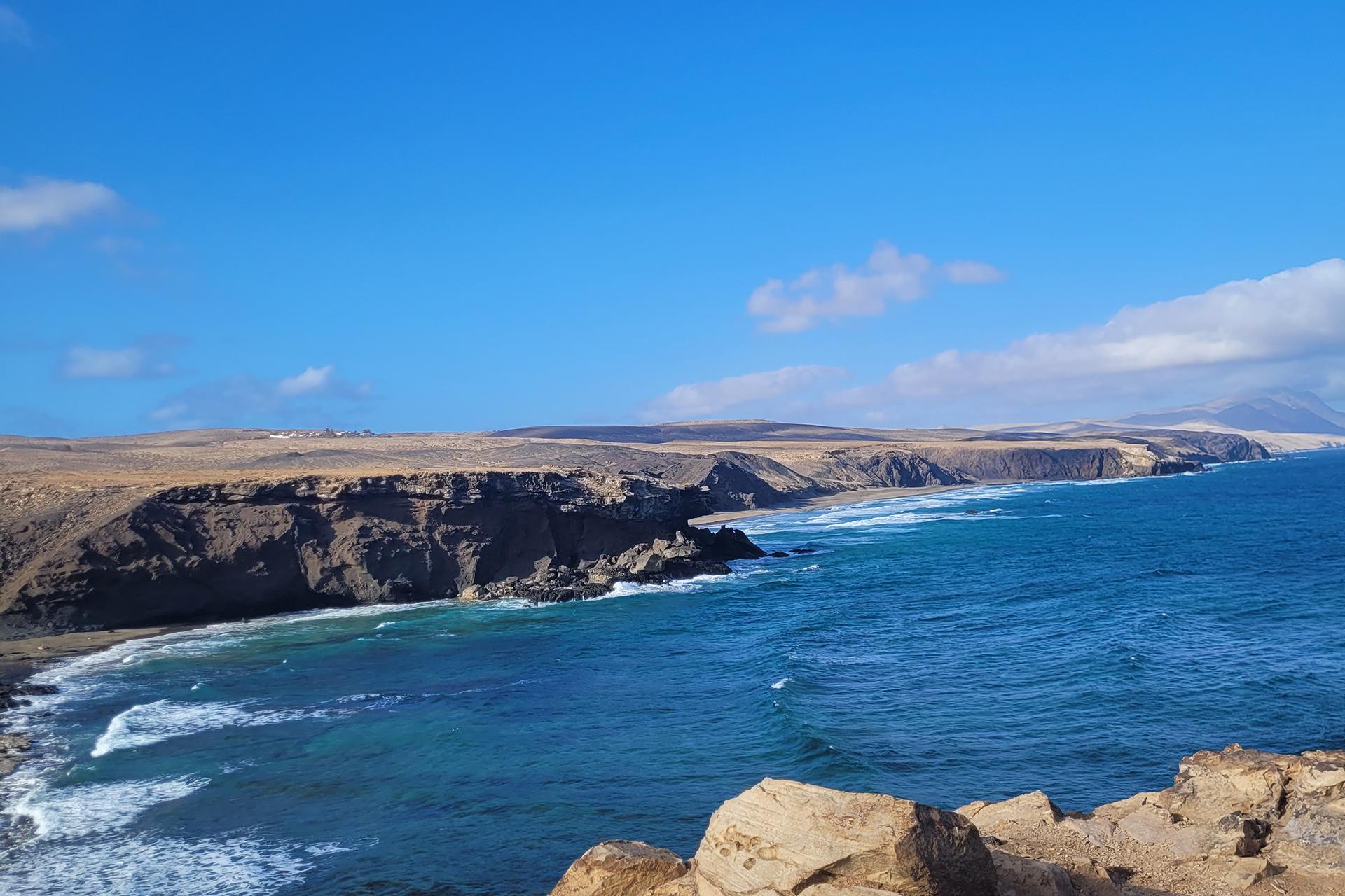 Klippen und felsige Küste mit blauem Meer unter klarem Himmel, ideal für Hotelurlaub am Meer.